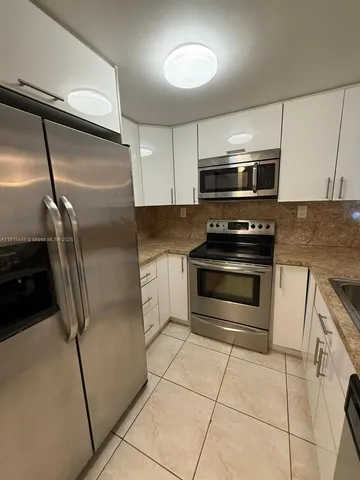 a kitchen with granite countertop a refrigerator and a stove top oven