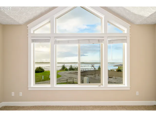 a view of empty room with wooden floor and window