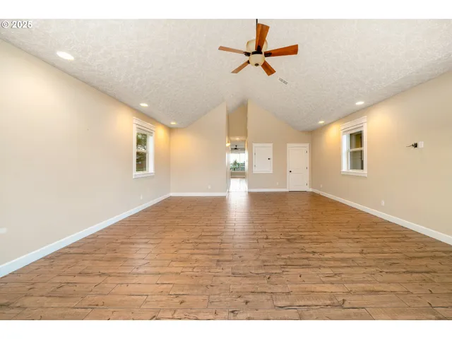 a view of an empty room with a window and wooden floor