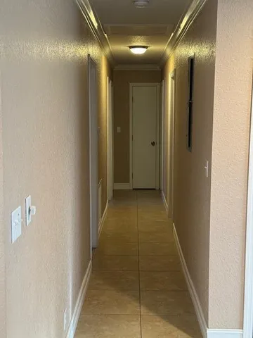 a view of an empty room with wooden floor and a ceiling fan