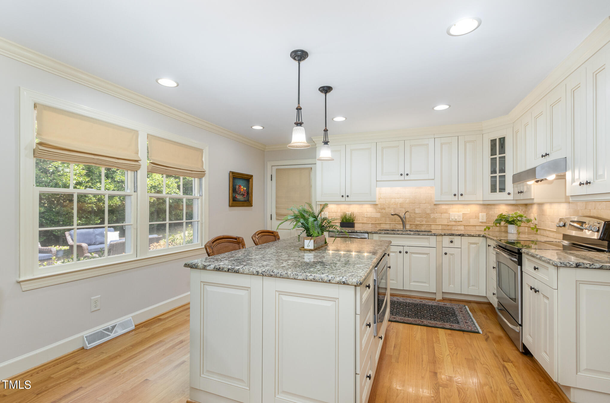 2901 Augusta Court Raleigh, NC 27607 - Photo 11 of 28 a kitchen with granite countertop a stove a sink and white cabinets with wooden floor