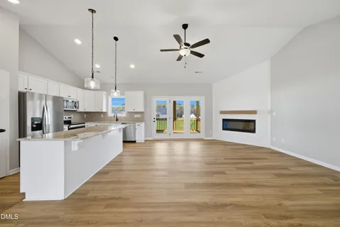 a large kitchen with kitchen island a stove a sink a refrigerator and a view of living room