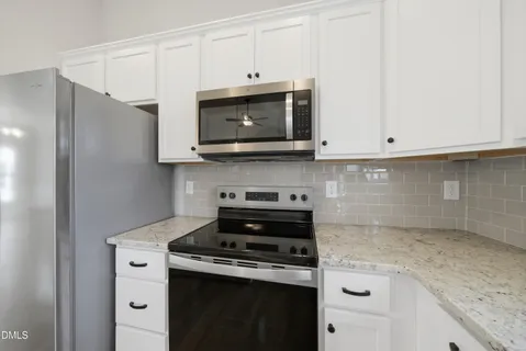 a kitchen with stainless steel appliances granite countertop white cabinets and a stove a oven with white countertops