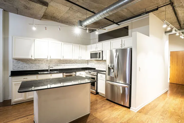 a kitchen with stainless steel appliances granite countertop a refrigerator a sink and a stove