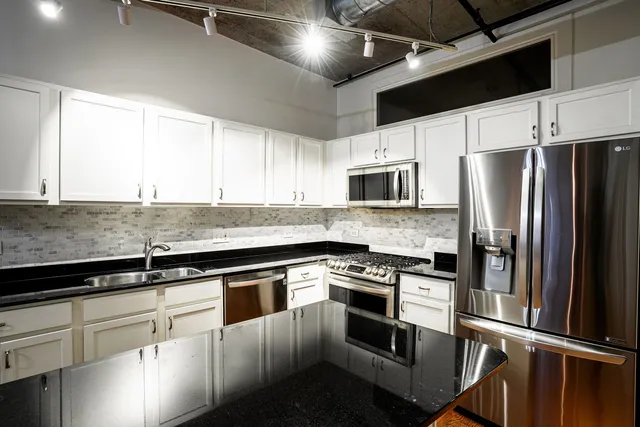 a kitchen with granite countertop a sink stainless steel appliances and cabinets