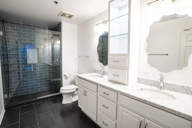 a bathroom with a double vanity sink toilet and shower