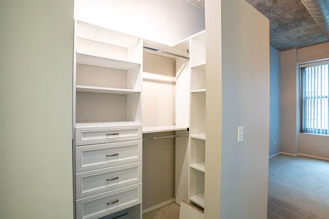 a walk in closet with wooden floor