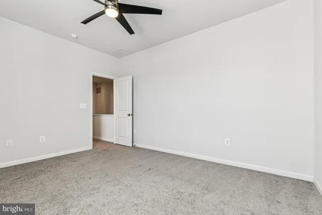 an empty room with a ceiling fan and carpet