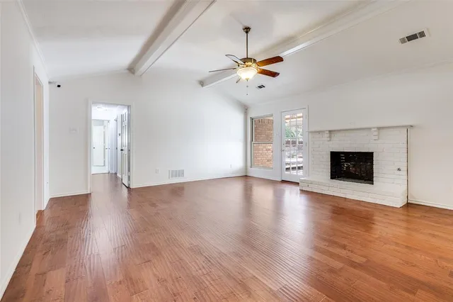 a view of empty room with wooden floor and fireplace