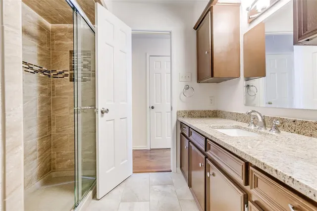 a bathroom with a granite countertop sink a mirror and shower