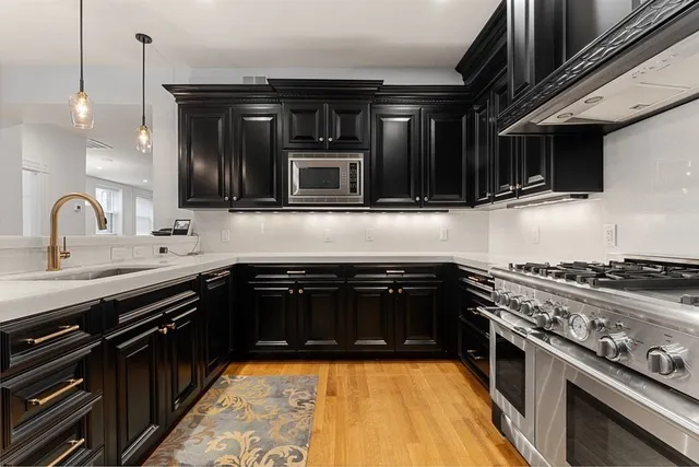 a kitchen with stainless steel appliances granite countertop a stove a sink and a microwave