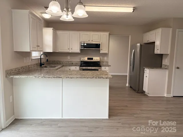 a kitchen with stainless steel appliances granite countertop a refrigerator a sink dishwasher a stove top oven a refrigerator and cabinets