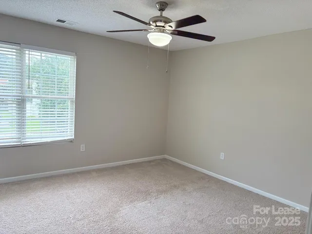 an empty room with a window and a fan