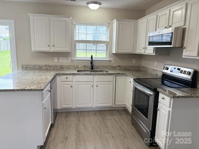 a kitchen with stainless steel appliances granite countertop a sink a stove a microwave and cabinets