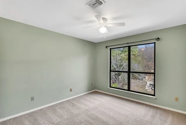 an empty room with windows and fan