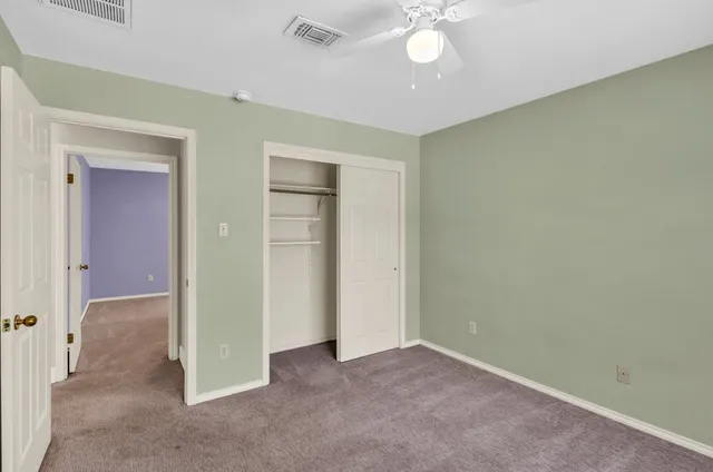 an empty room with a chandelier fan and windows