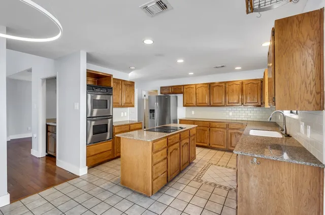 a kitchen with stainless steel appliances granite countertop a sink and a refrigerator