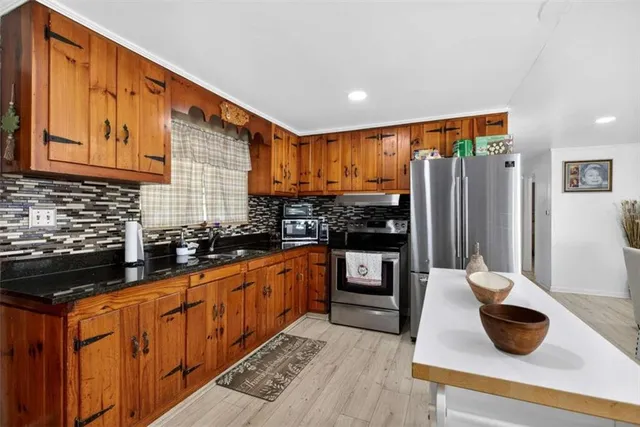a kitchen with stainless steel appliances a stove a refrigerator a sink a dining table and chairs