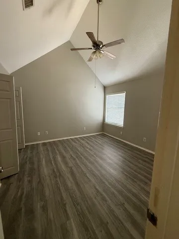 an empty room with wooden floor fan and windows