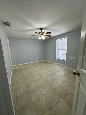 a view of an empty room with a ceiling fan and window