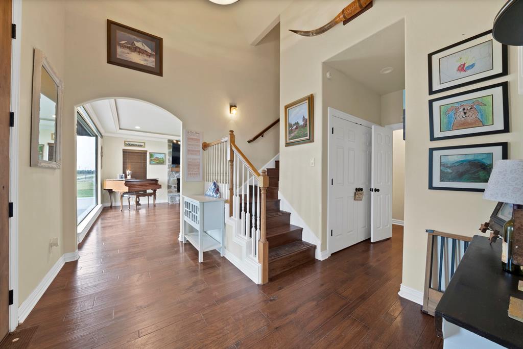 100 Shadle Ridge Court Poolville, TX 76487 - Photo 2 of 40 Foyer featuring wood-finish flooring, an arched doorway, and a staircase with white balusters