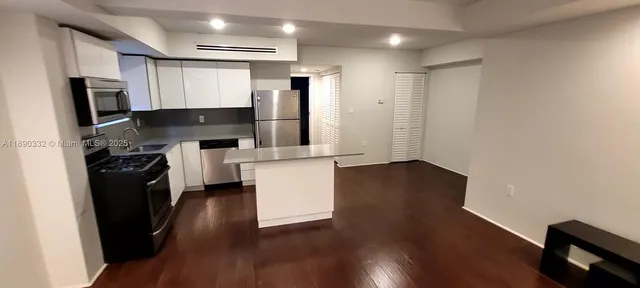 a kitchen with granite countertop a refrigerator a sink and wooden floor