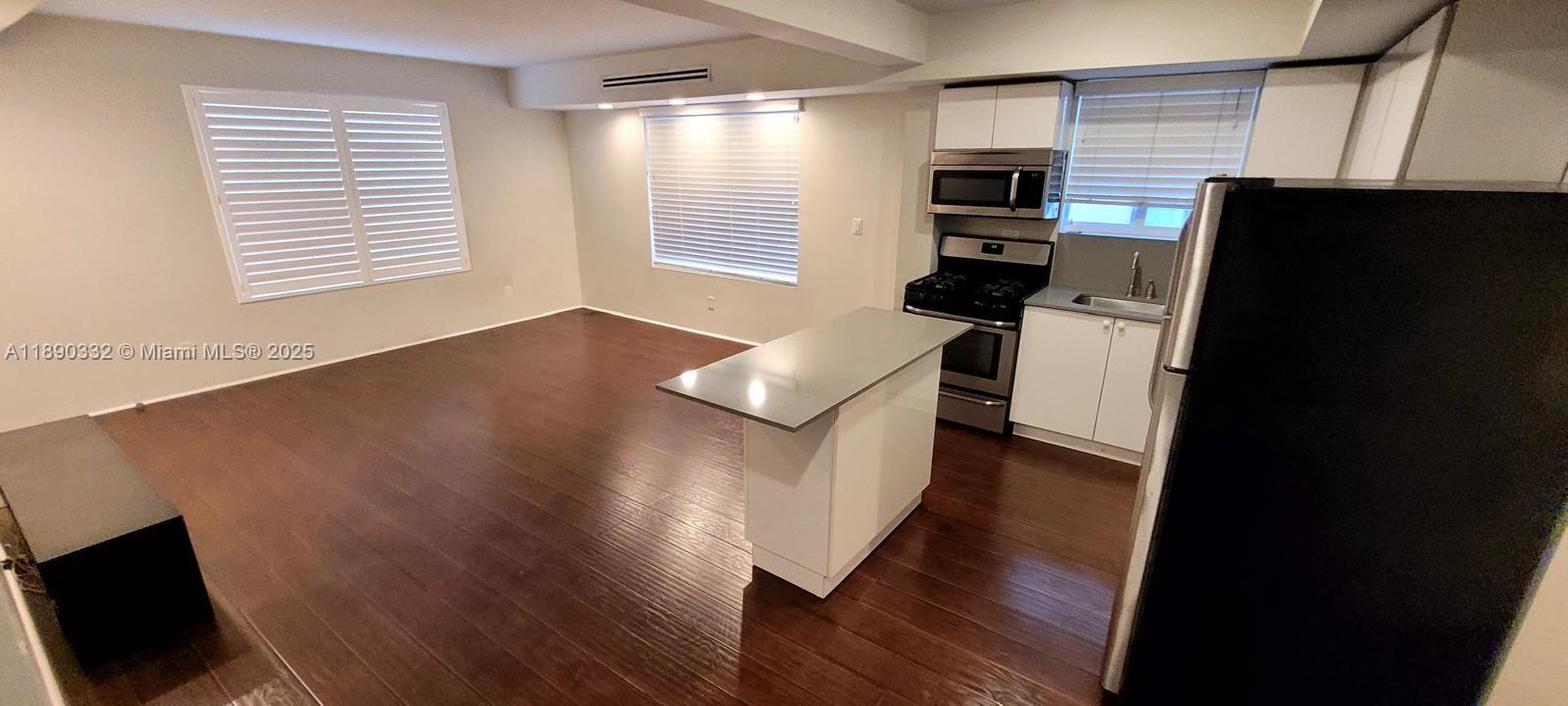 7333 Dickens Avenue, Unit 1 Miami Beach, FL 33141 - Photo 2 of 12 a kitchen with stainless steel appliances granite countertop a refrigerator a stove a microwave oven a sink and dishwasher with wooden floor