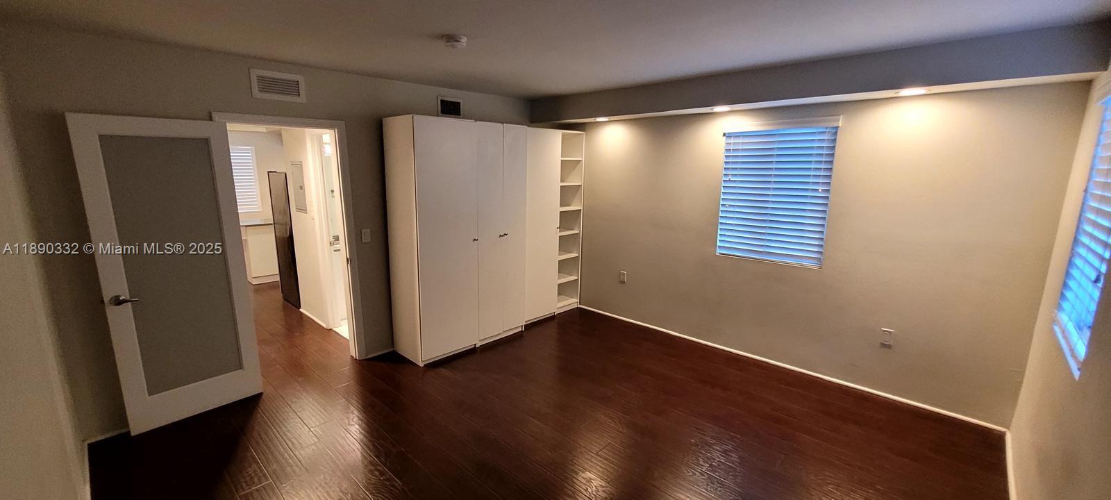7333 Dickens Avenue, Unit 1 Miami Beach, FL 33141 - Photo 7 of 12 a view of an empty room with wooden floor and a window