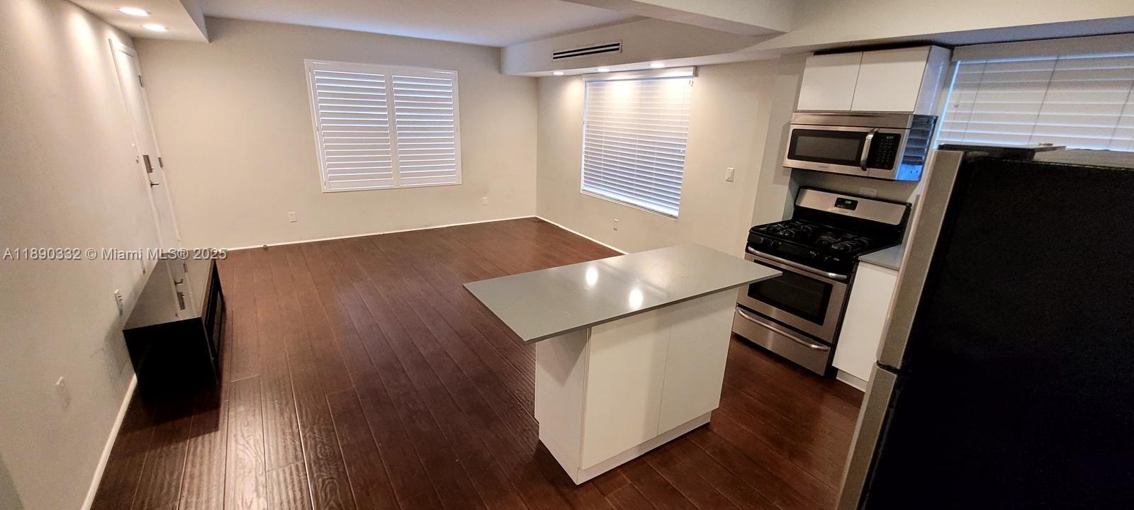 7333 Dickens Avenue, Unit 1 Miami Beach, FL 33141 - Photo 10 of 12 a kitchen with a refrigerator stove and wooden cabinets