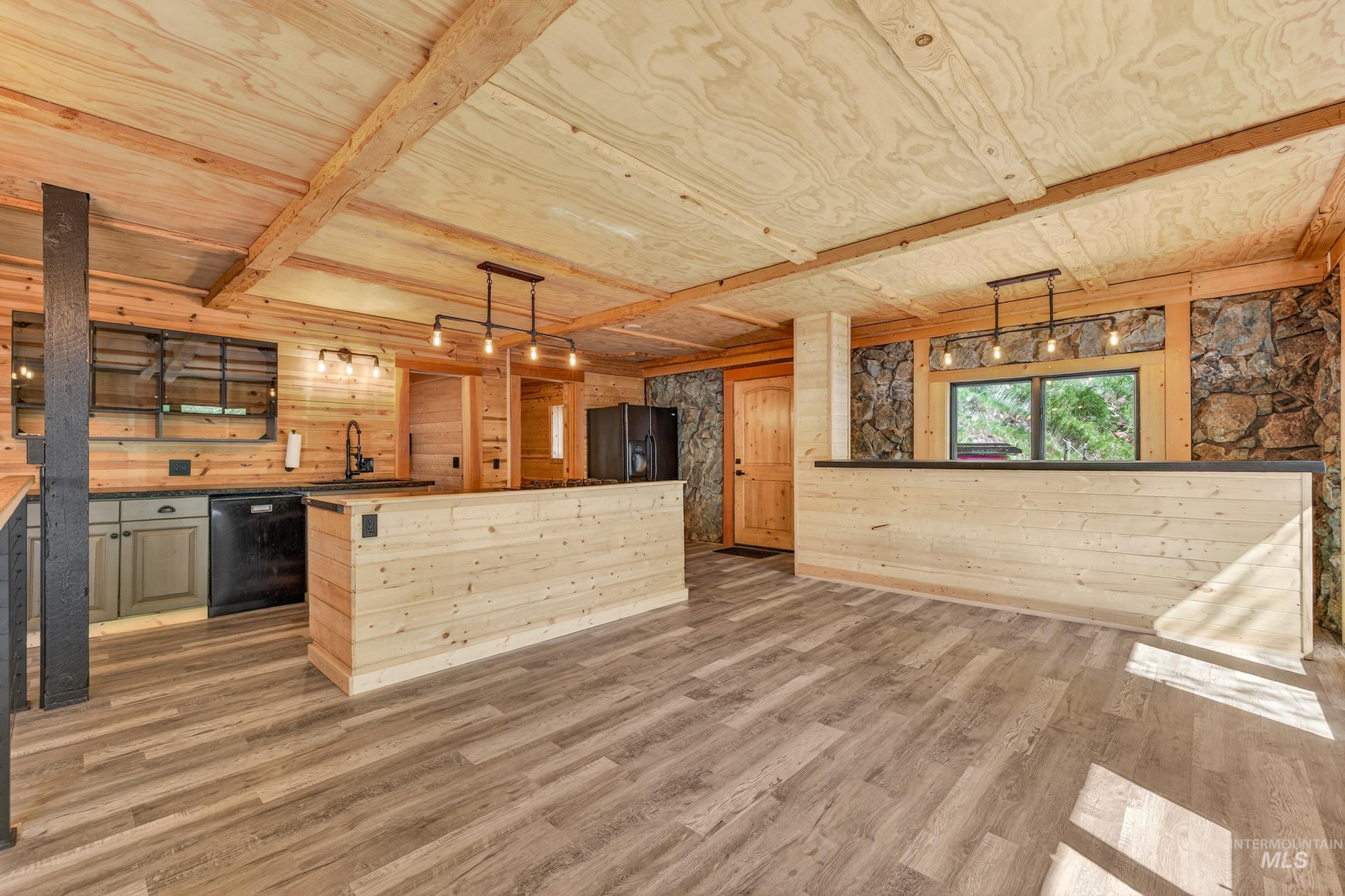543 North Main Street Riggins, ID 83549 - Photo 11 of 46 Kitchen with light wood-style flooring, black appliances, decorative light fixtures, wood walls, and a center island