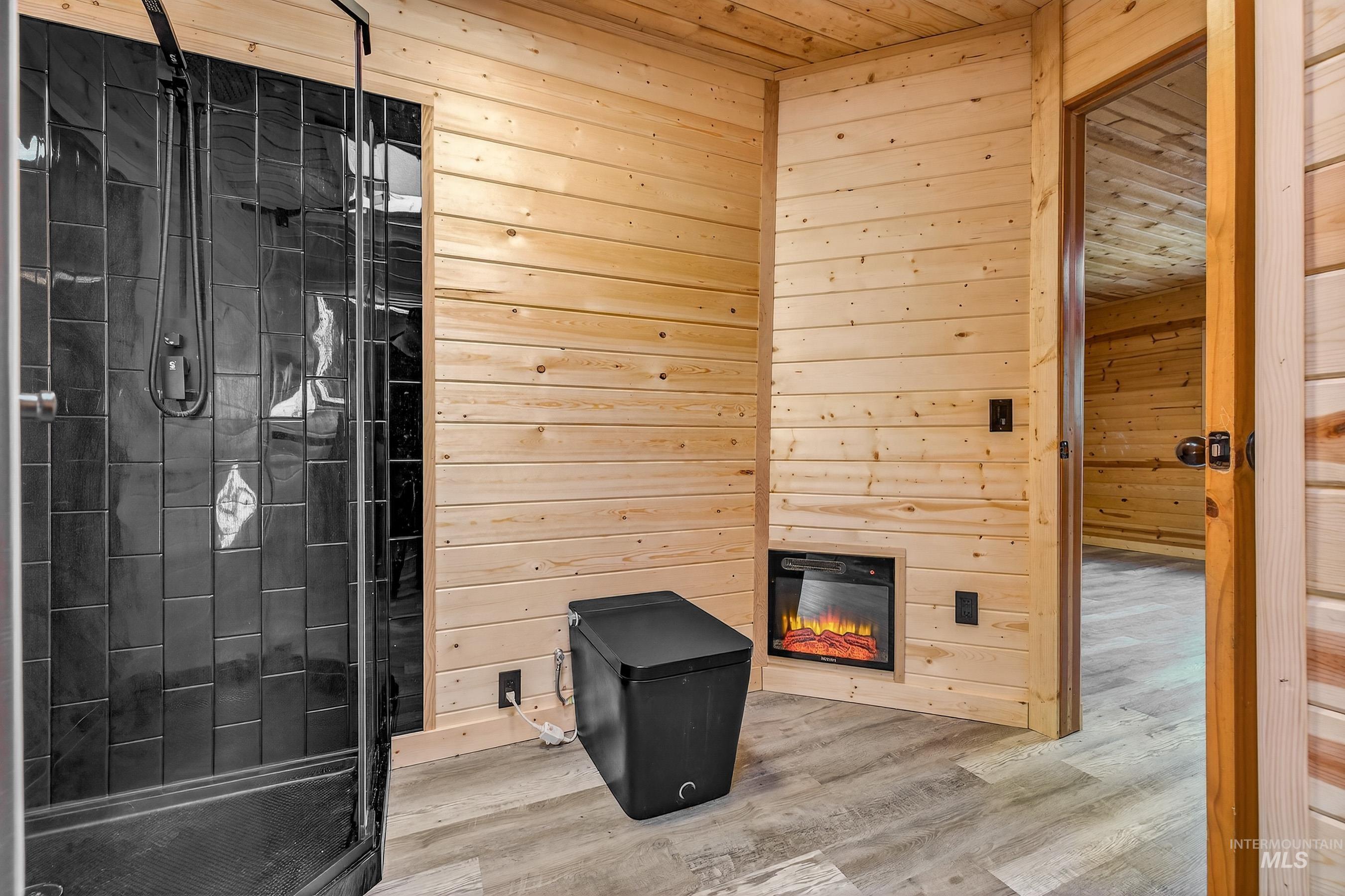 543 North Main Street Riggins, ID 83549 - Photo 25 of 46 Full bathroom featuring wood walls, a stall shower, a glass covered fireplace, wooden ceiling, and wood finished floors