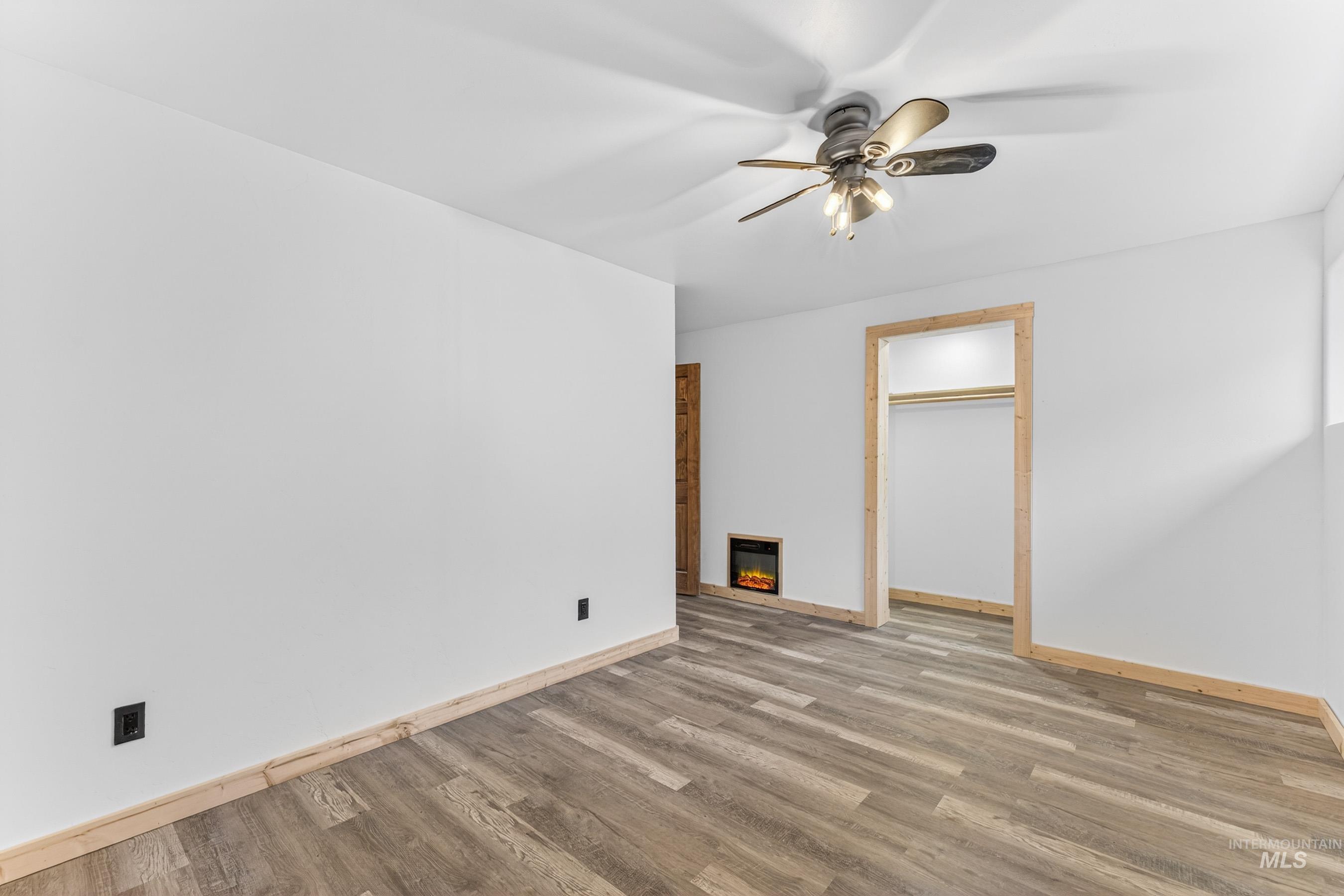 543 North Main Street Riggins, ID 83549 - Photo 39 of 46 Unfurnished bedroom with light wood-style floors, a glass covered fireplace, a ceiling fan, heating unit, and a spacious closet