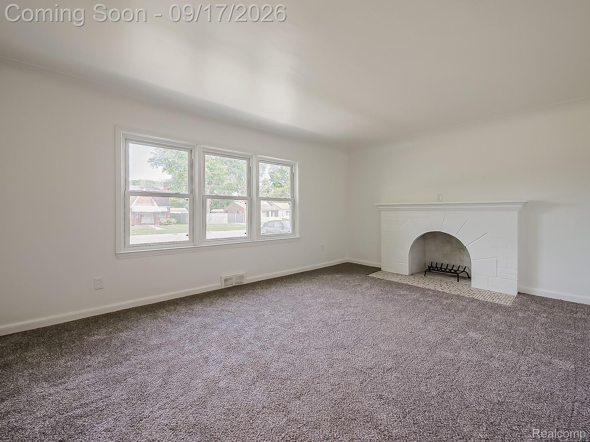 14102 Toepfer Road Warren, MI 48089 - Photo 32 of 39 White interior walls with a triple window unit, a fireplace with a tiled hearth, and gray carpeting