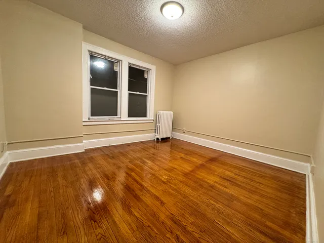 a view of an empty room with wooden floor and windows