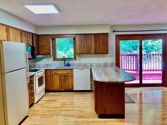 a kitchen with stainless steel appliances granite countertop a refrigerator a sink dishwasher and wooden cabinets with a large window