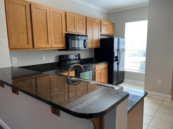 a kitchen with stainless steel appliances granite countertop a sink a microwave a refrigerator and a stove