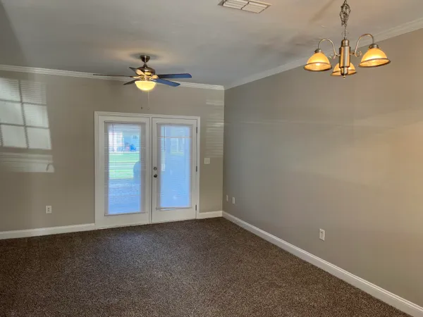 an empty room with a chandelier fan and windows