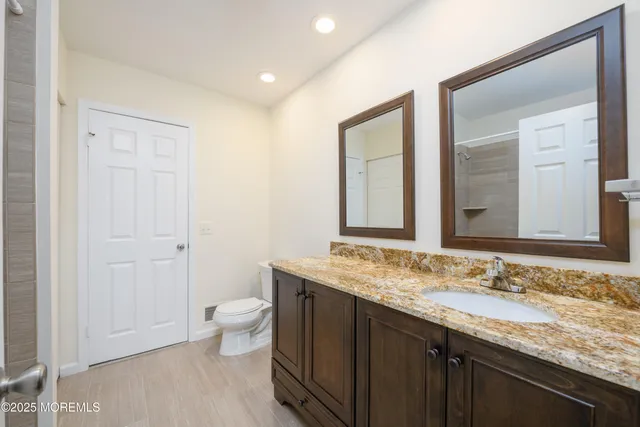 a bathroom with a granite countertop sink a toilet and a mirror
