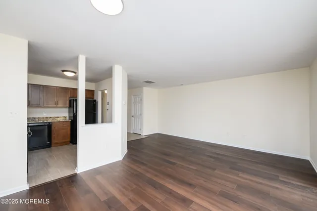 a view of kitchen and empty room with wooden floor