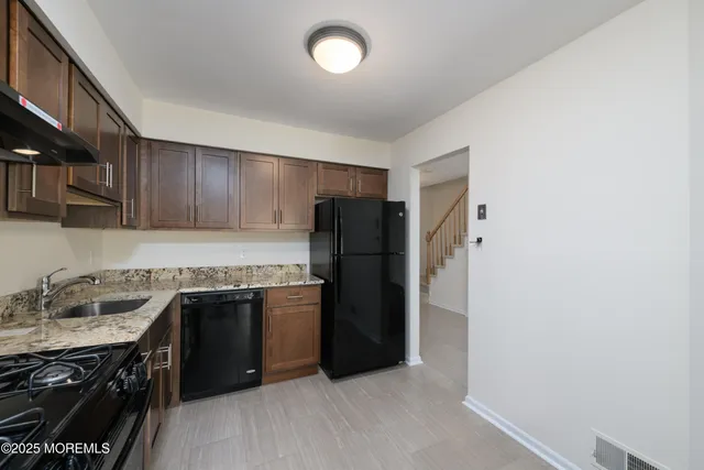 a kitchen with stainless steel appliances granite countertop a refrigerator and a stove top oven