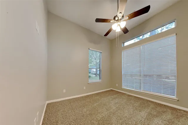 an empty room with windows and fan