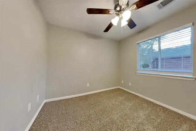 an empty room with windows and chandelier fan