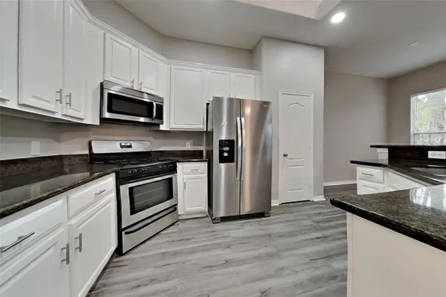 a kitchen with stainless steel appliances granite countertop a stove a refrigerator and a microwave