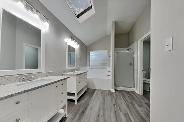 a spacious bathroom with a granite countertop double vanity sink a mirror and a shower