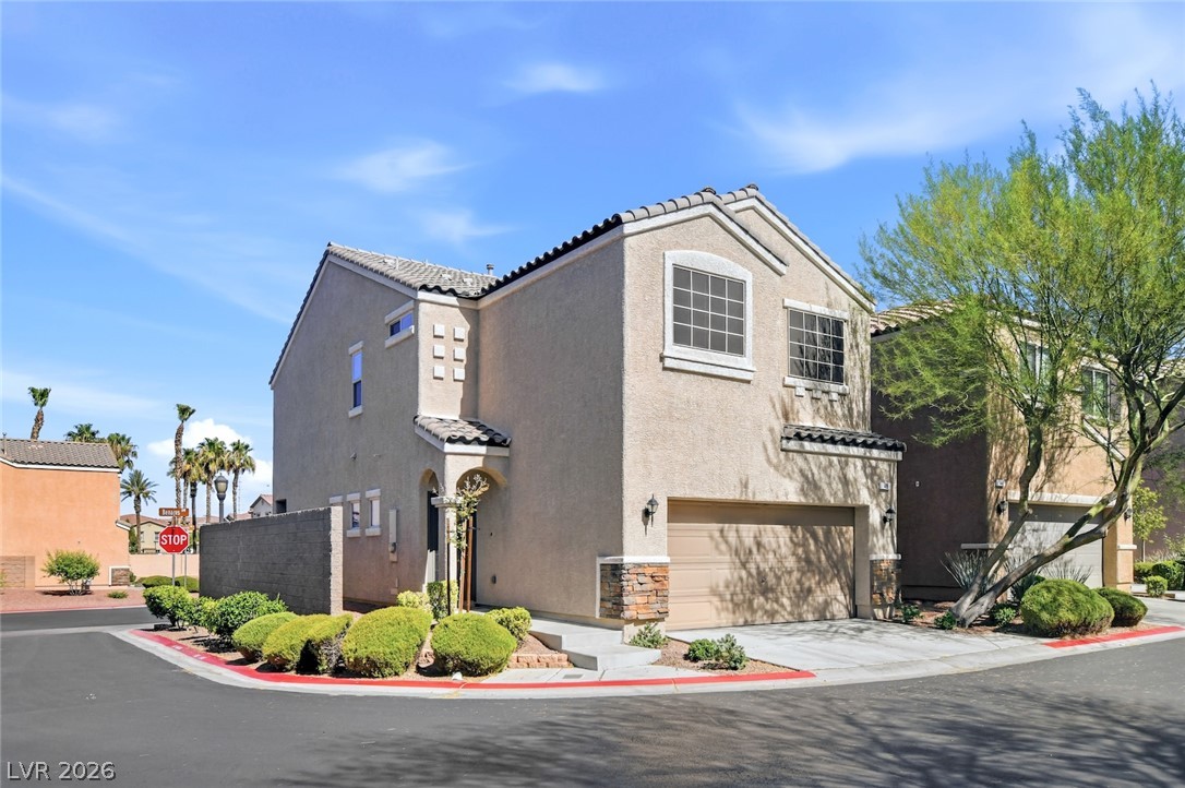 48 Jasmine Point Street Henderson, NV 89074 - Photo 58 of 62 A corner lot residence, showcasing a garage and manicured landscaping under a clear sky.