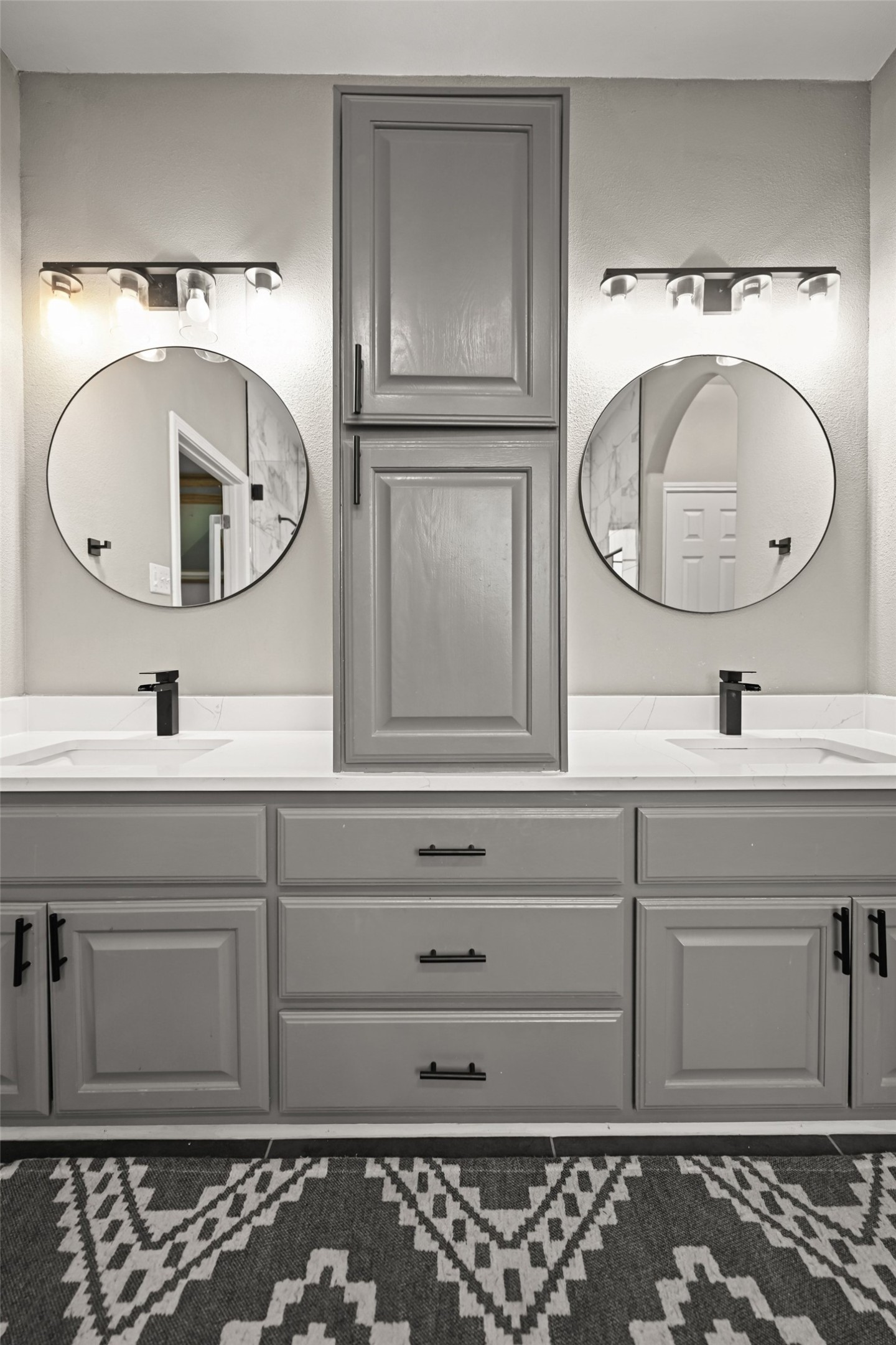 5528 Wild Foxglove Road Spicewood, TX 78669 - Photo 15 of 38 Dual vanity with white countertops and matte black fixtures, framed by circular mirrors and overhead lighting