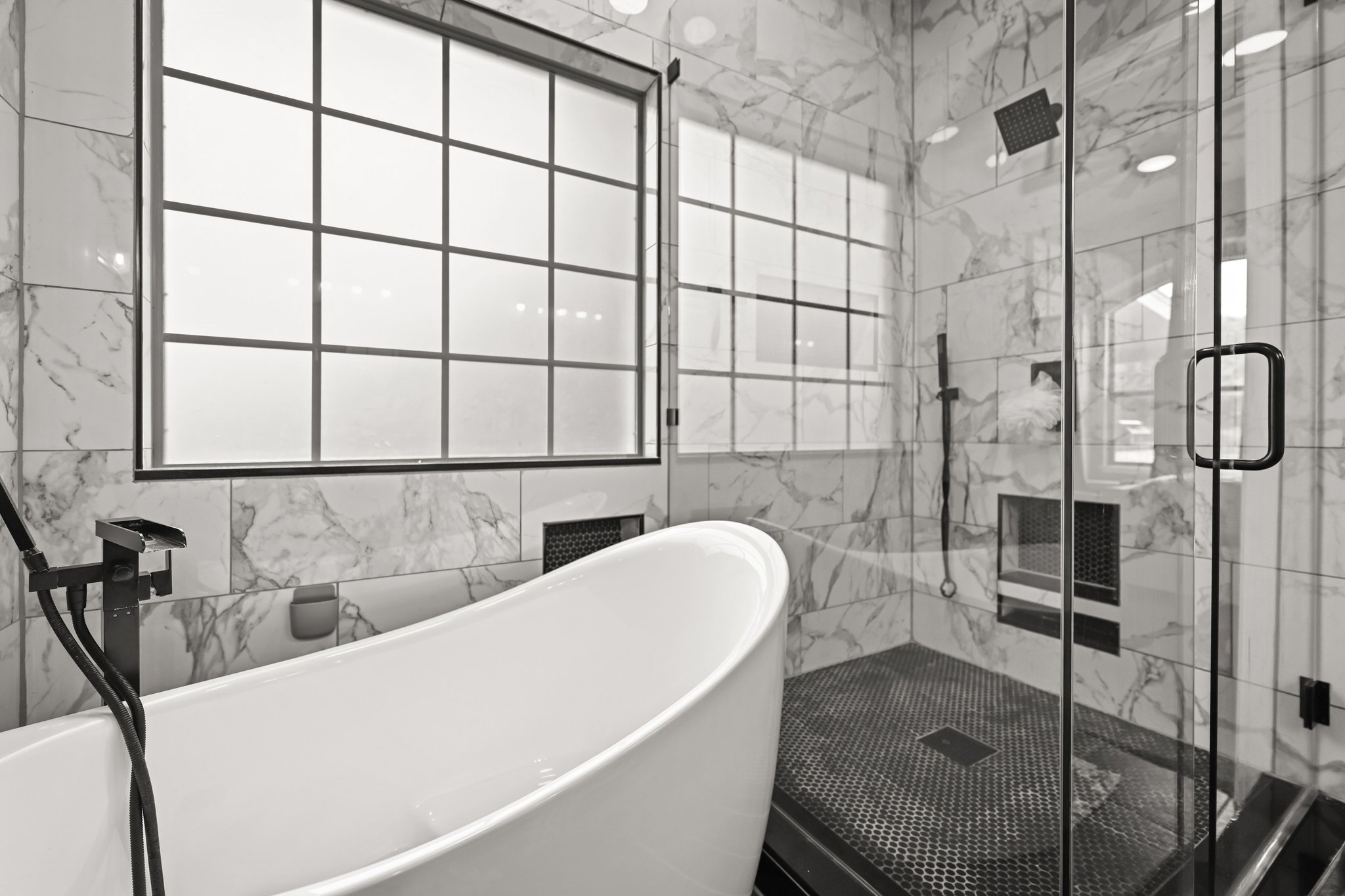 5528 Wild Foxglove Road Spicewood, TX 78669 - Photo 16 of 38 Contemporary bathroom featuring a freestanding tub with matte black fixtures, a spacious glass-enclosed shower with a rain showerhead, and white marble-look wall tiling