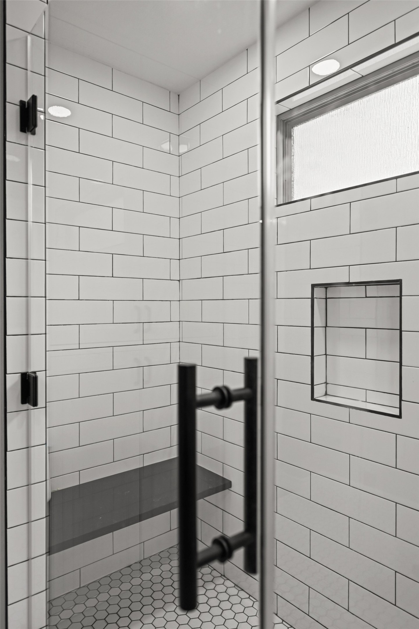 5528 Wild Foxglove Road Spicewood, TX 78669 - Photo 19 of 38 Modern shower enclosure featuring white subway tile, a built-in bench, hexagon floor tile, and matte black hardware