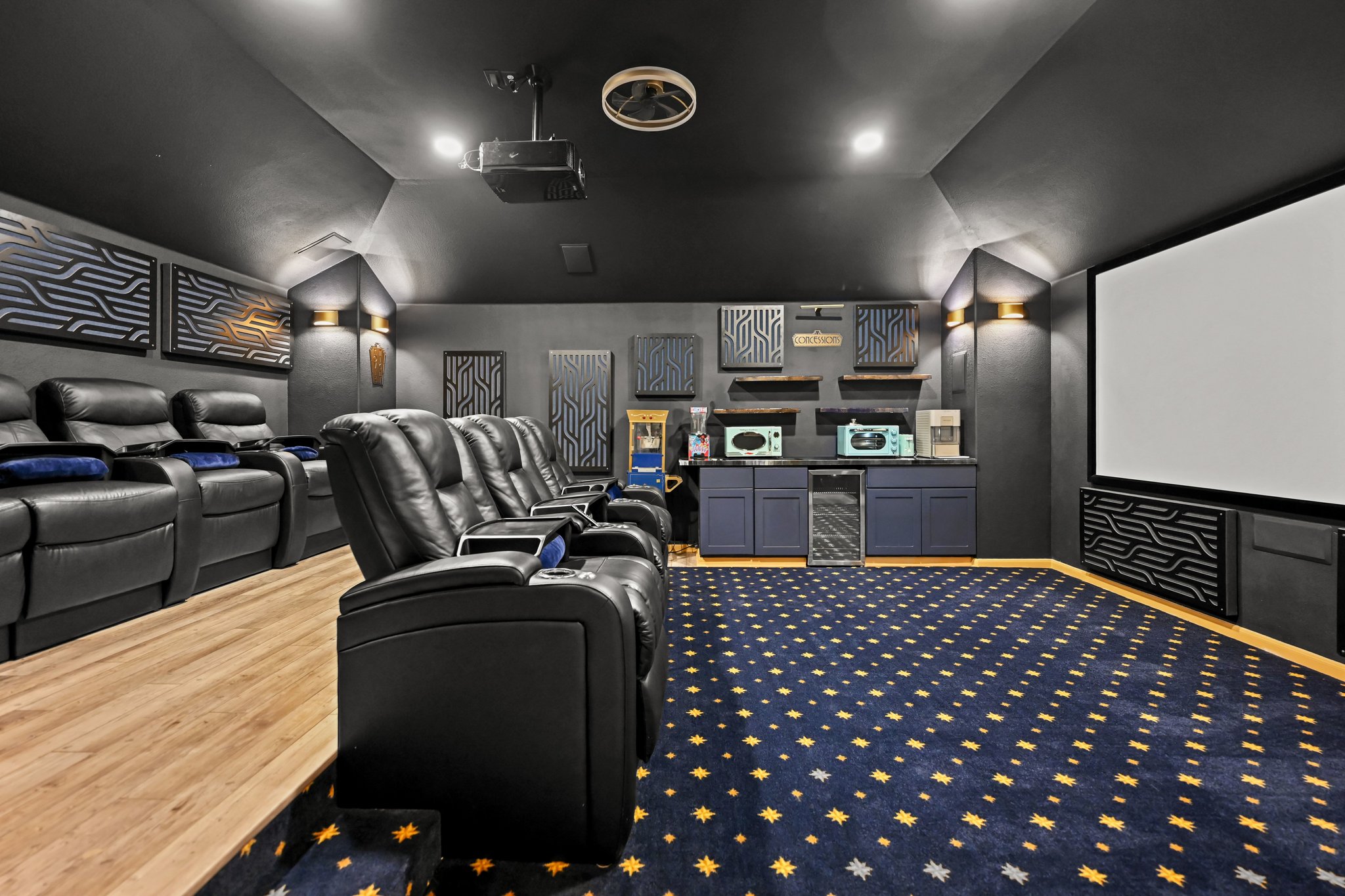 5528 Wild Foxglove Road Spicewood, TX 78669 - Photo 22 of 38 Dedicated media room featuring tiered seating, a large projection screen, a built-in snack bar with cabinetry, and patterned carpet flooring