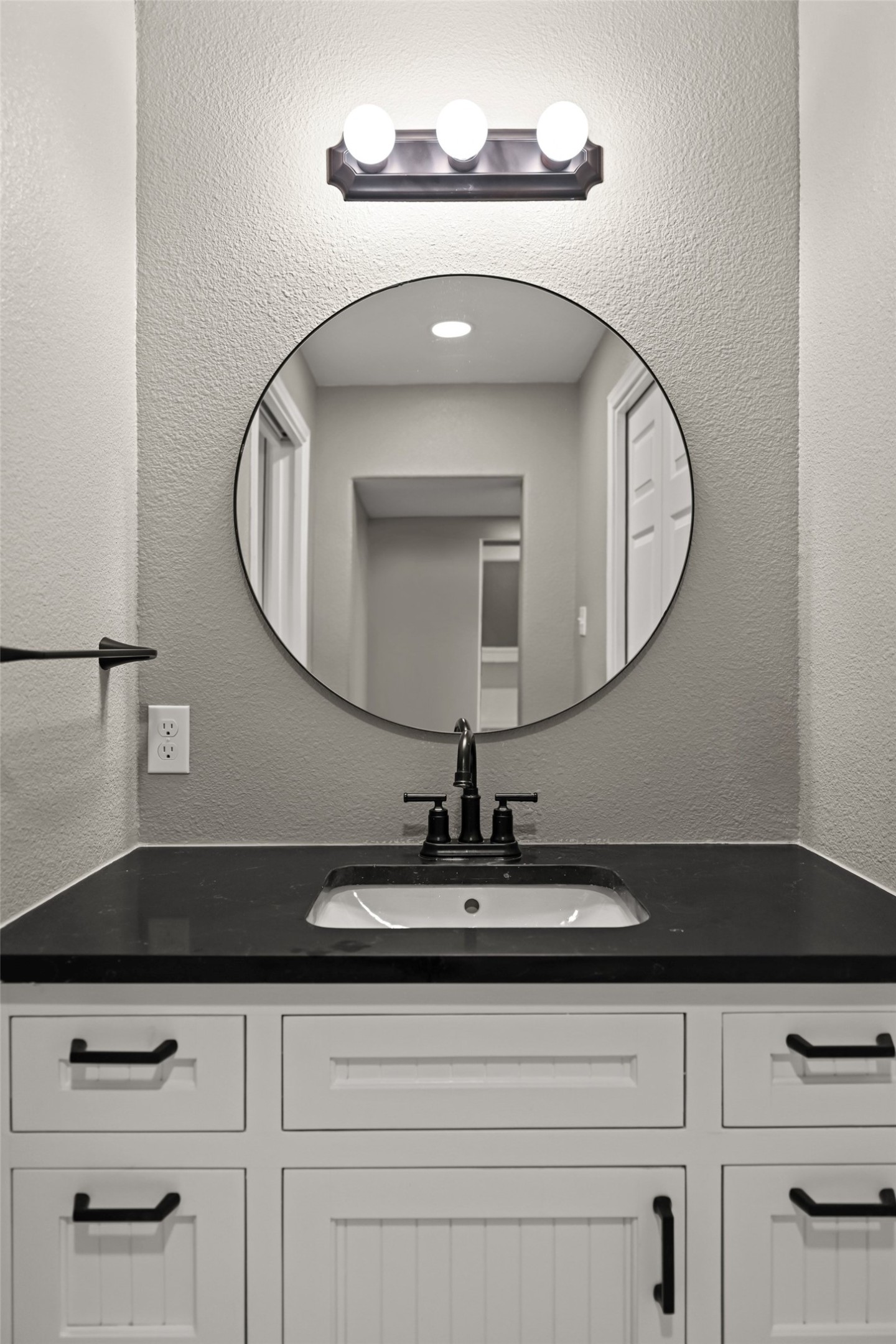 5528 Wild Foxglove Road Spicewood, TX 78669 - Photo 30 of 38 Vanity with a black countertop, undermount sink, and black faucet hardware